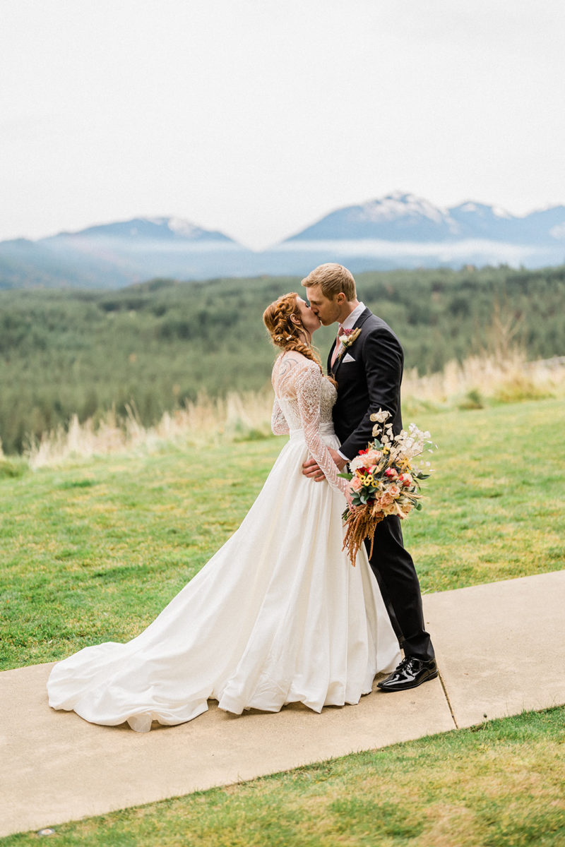 Bride and groom kiss outside at Swiftwater Cellars mountains in background