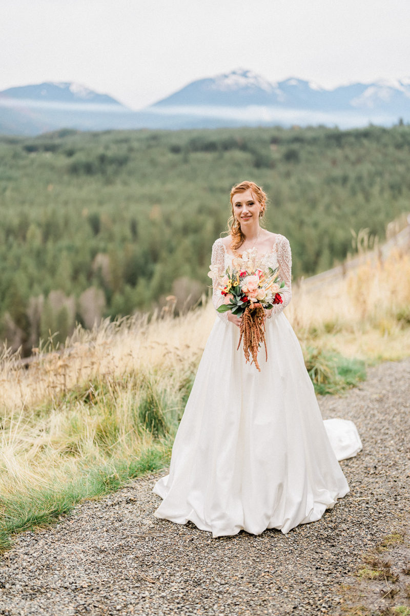 Bride smiles with bouquet outside at Swiftwater Cellars