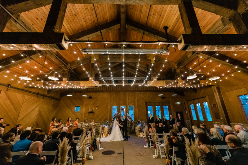 Beautiful bride and groom holding hands with lights inside Swiftwater Cellars