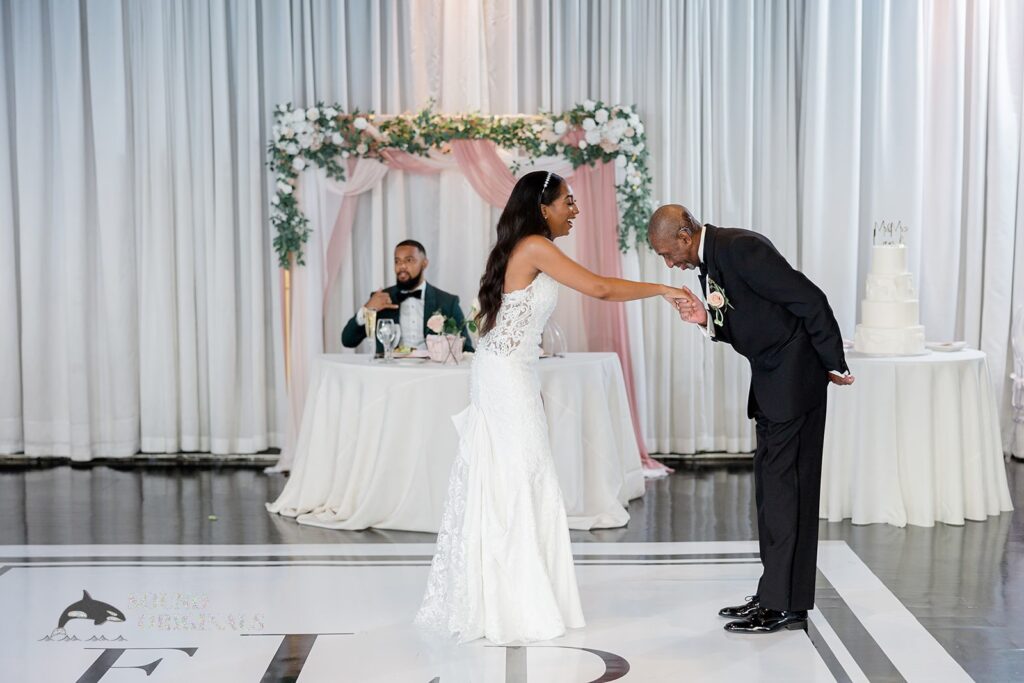 Father takes daughter&#039;s hand and bows asking her for a dance at Briza on the Bay Wedding