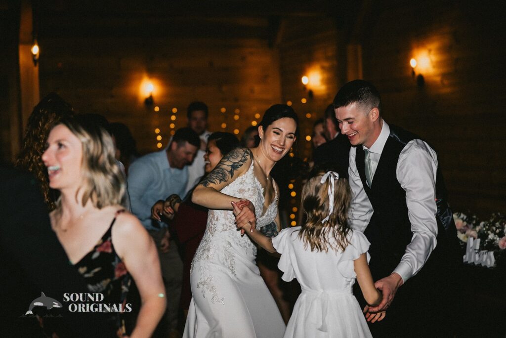 Bride and groom show off different dance steps with flower girl in the Stoneyman Valley Ranch Wedding