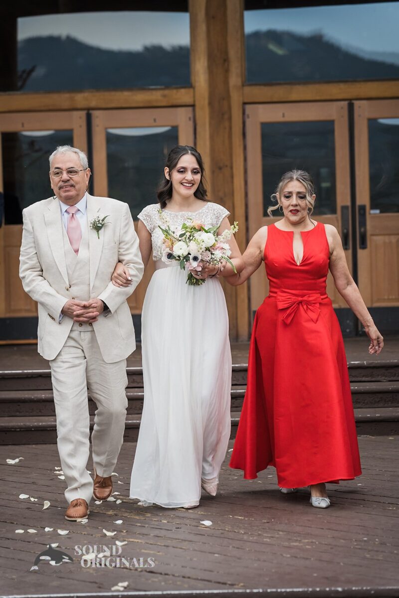 Beautiful bride and parents walking out of Evergreen Lake House indoors to the outdoors for an Evergreen Lake House Wedding