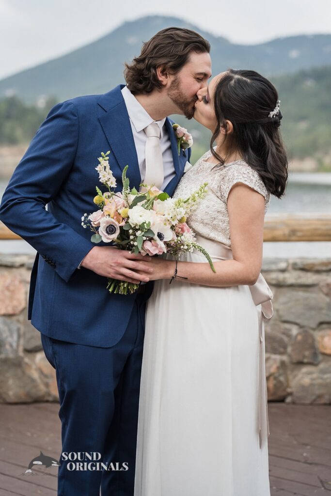 Evergreen Lake House Wedding bride and groom takes a romantic kiss beside the venue&#039;s lake